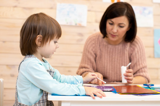 Female teacher play teaches preschooler child in day care center