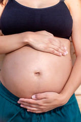 Pregnant woman poses with hands on belly
