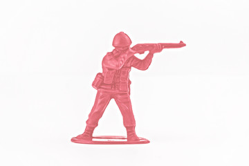 Little pink toy plastic soldier aiming their gun isolated on a white background, shot from the side.