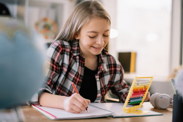 Beautiful girl learning at home. Schoolgirl doing homework. 