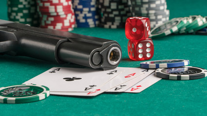 Poker chips, cards and gun on a green background. The concept of gambling and entertainment. Casino...