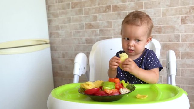 Child feeding cat at home. Little girl playing with kitten in light kitchen. Domestic animals and pets for children