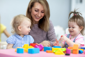 Obraz na płótnie Canvas children toddlers playing with teacher in nursery or daycare