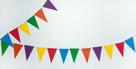 The concept of the birthday in the style of minimalism. Two garlands of multi-colored triangle paper flags on a white background. Free space.