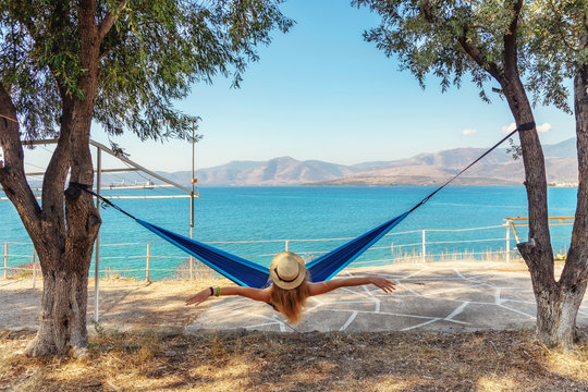 Girl sitting in a hammock on a background of blue Aegean Sea