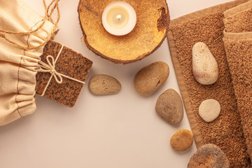 Spa and wellness concept, natural coffee scrub soap in cotton eco bag, coconut oil cosmetic, peeling sand stone,towel,wooden haircomb.Beige dayspa set.Pastel bathroom accessories and products top view