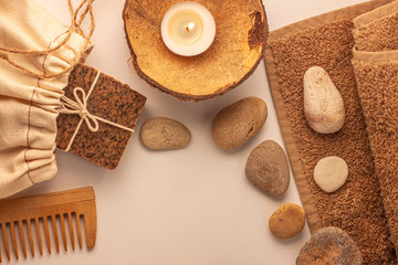 Fototapeta na wymiar Spa and wellness concept, natural coffee scrub soap in cotton eco bag, coconut oil cosmetic, peeling sand stone,towel,wooden haircomb.Beige dayspa set.Pastel bathroom accessories and products top view