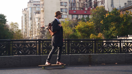Hipster businessman skateboarding at the bridge at sunny day - Powered by Adobe