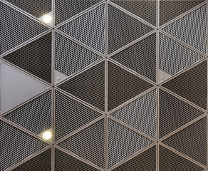 Seamless texture of the system of suspended ceilings with metal profiles and metal mesh with built-in lights and spots. Gray ceiling with triangular cells. Wall design