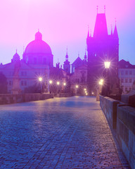 Charles Bridge at dawn, silhouette of Bridge Tower and saint sculptures with illumination in Prague, Czech Republic