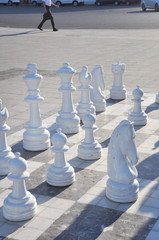 Large white chess pieces for outdoor play.  Сhessboard on the street sidewalk with figures