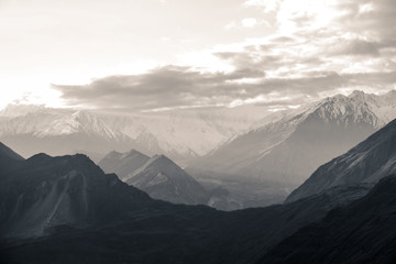 Nature aerial landscape view black and white photo of sunrise over snow capped Karakoram mountain range with morning fog in Nagar valley. Gilgit Baltistan, Pakistan. - Powered by Adobe