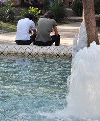 Two friends resting near the fountain  in a park