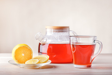 Cup and teapot with tea, lemon on table. Fruit tea with slice of citrus.