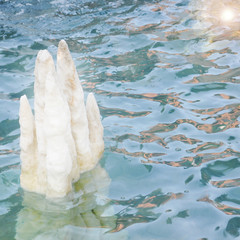 Salt crystals protruding from the water surface of turquoise color in the lake. Picture for relaxation with rippling water and crystal
