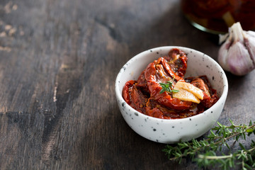 sun-dried tomatoes in a plate on a dark wooden background.
