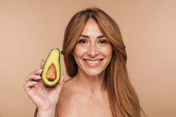 Portrait of shirtless adult woman holding avocado and smiling