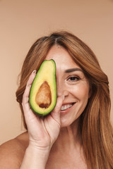 Portrait of shirtless adult woman holding avocado and smiling