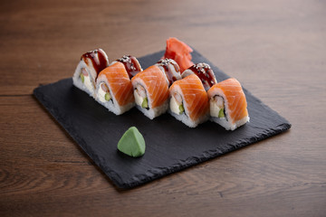 Appetizing sushi set on a stone plate on a dark wooden table
