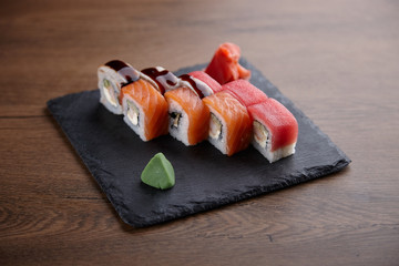 Appetizing sushi set on a stone plate on a dark wooden table