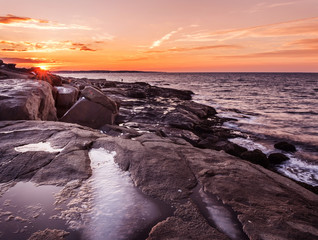 Icy stones on the shore of the Atlantic Ocean at dawn. Winter dawn on the ocean.