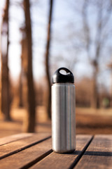 Trinkflache auf Holztisch. Wandern im Herbst. Thermosflasche. Sports water bottle on wooden table,...