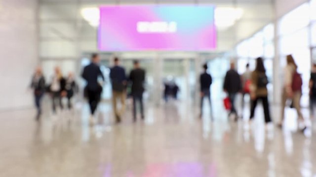 Blurred convention center hallway with people passing