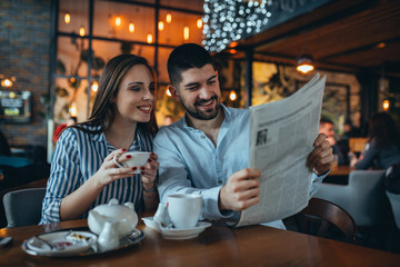 romantic couple in restaurant drinking tea and reading press