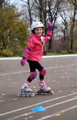 Roller skating  happy little girl in park rollerblading on inline skates. Caucasian girl in outdoor...