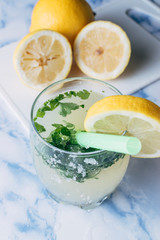 Close-up of a glass of lemonade with aromatic herbs with the lemons cut from the bottom