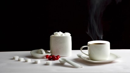 White coffee mug with coffee and lumps of sugar on a black background
