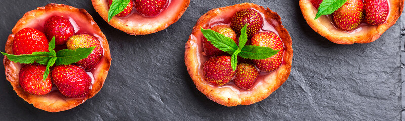 Banner of Homemade strawberries tarts on slate plate, black background.