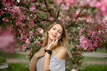 Obraz na płótnie Canvas Portrait of a beautiful girl among spring foliage and flowers