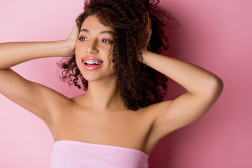 beautiful positive african american girl with dental braces on pink