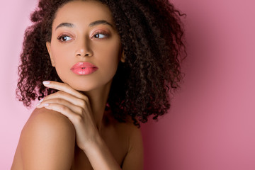 portrait of attractive curly nude african american girl on pink