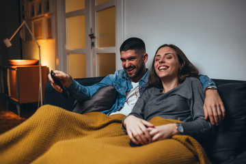happy couple watching television relaxed in sofa at home