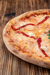 Baked seafood pizza with melted cheese and ketchup on wooden background