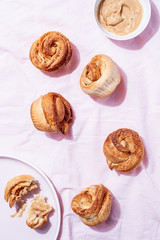 Trendy modern pastries cruffins (Croissant and Muffin) with cinnamon,brown sugar and vegan creamy nut cashew butter spread on pink textile background. Concept of breakfast or brunch.Top view, flat lay
