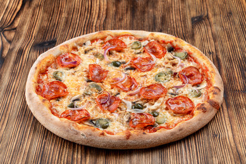 Very hot and spicy pizza with jalapeno, pepperoni and red onion on wooden background