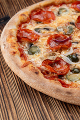 Very hot and spicy pizza with jalapeno, pepperoni and red onion on wooden background