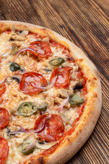 Very hot and spicy pizza with jalapeno, pepperoni and red onion on wooden background