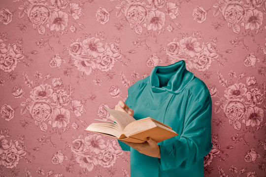 Woman with no head reading book while standing against wall