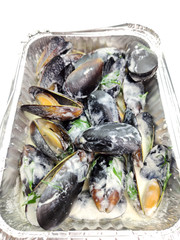 Mussels in cream cheese sauce and garlic. Mussels in a package for delivery on a white background