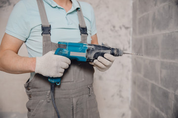 Builder man with pneumatic hammer drill perforator with diamond crown making hole in wall for...