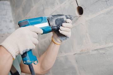 Builder man with pneumatic hammer drill perforator with diamond crown making hole in wall for...