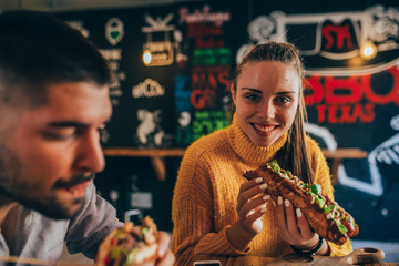 portrait of woman eating sausage burger