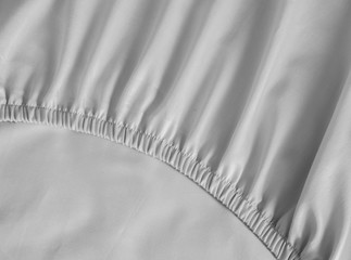 Bed corner with white fitted sheet. White sheet with elastic band. Flat sheet or bed cover. - obrazy, fototapety, plakaty