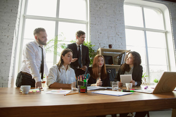 Positive. Group of young business professionals having a meeting. Diverse group of coworkers discussing new decisions, plans, results, strategy. Creativity, workplace, business, finance, teamwork.