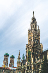The New Town Hall, Neues Rathaus on Marienplatz main square, city government building with a tower clock. Gothic style. Photographed from below. Wide shot with Munich Frauenkirche in background. Wide 