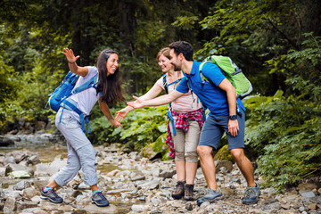 Wanderer die ein bergfluss überqueren und dabei spass haben.